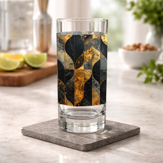 Aged Elegance highball glass with black and bronze design on a kitchen counter with shaker and bowl of nuts in background
