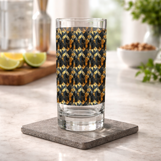Aged Elegance highball glass with black and bronze design on a kitchen counter with shaker and bowl of nuts in background