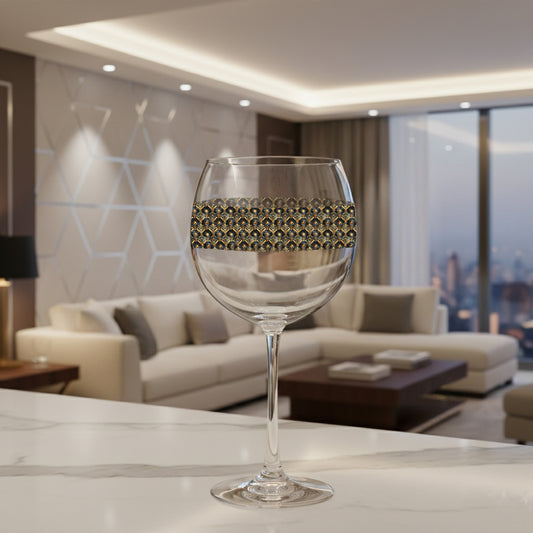 Astral Glow balloon wine glass with a black and bronze design on a counter with a modern living room in the background