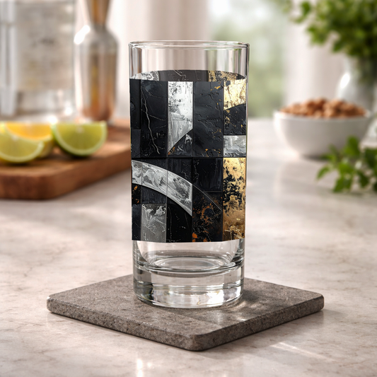 Frescro Fragments highball glas with black, silver, and gold design on a kitchen counter with shaker and a bowl of snacks blurred in the background