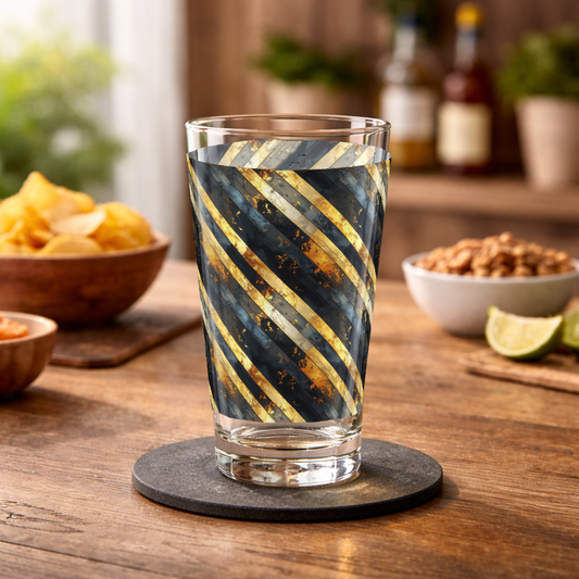 Obsidian Stripes pint beer glass with black and gold striped pattern on a wood surface along ith chips and nuts