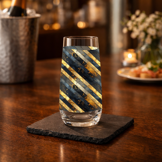 Obsidian Stripes stemless champagne glass with gold and black diagonal design on a kitchen counter