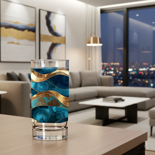 Opulent Teal highball glass with teal and gold wavy design on a table in a modern living room with sectional, abstract art, and large window with city views