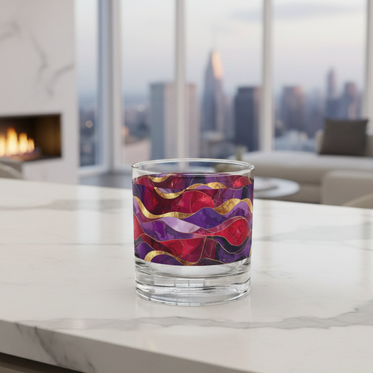 Fluid Marble rocks glass with purple and gold design sitting on an a marble countertop, and a modern fireplace, sofa and large window with city view in background