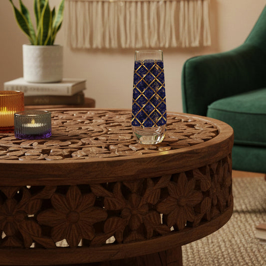 Regal Twilight stemless champagne glass with sapphire and gold wrap design on a wooden table in a cozy living room setting.