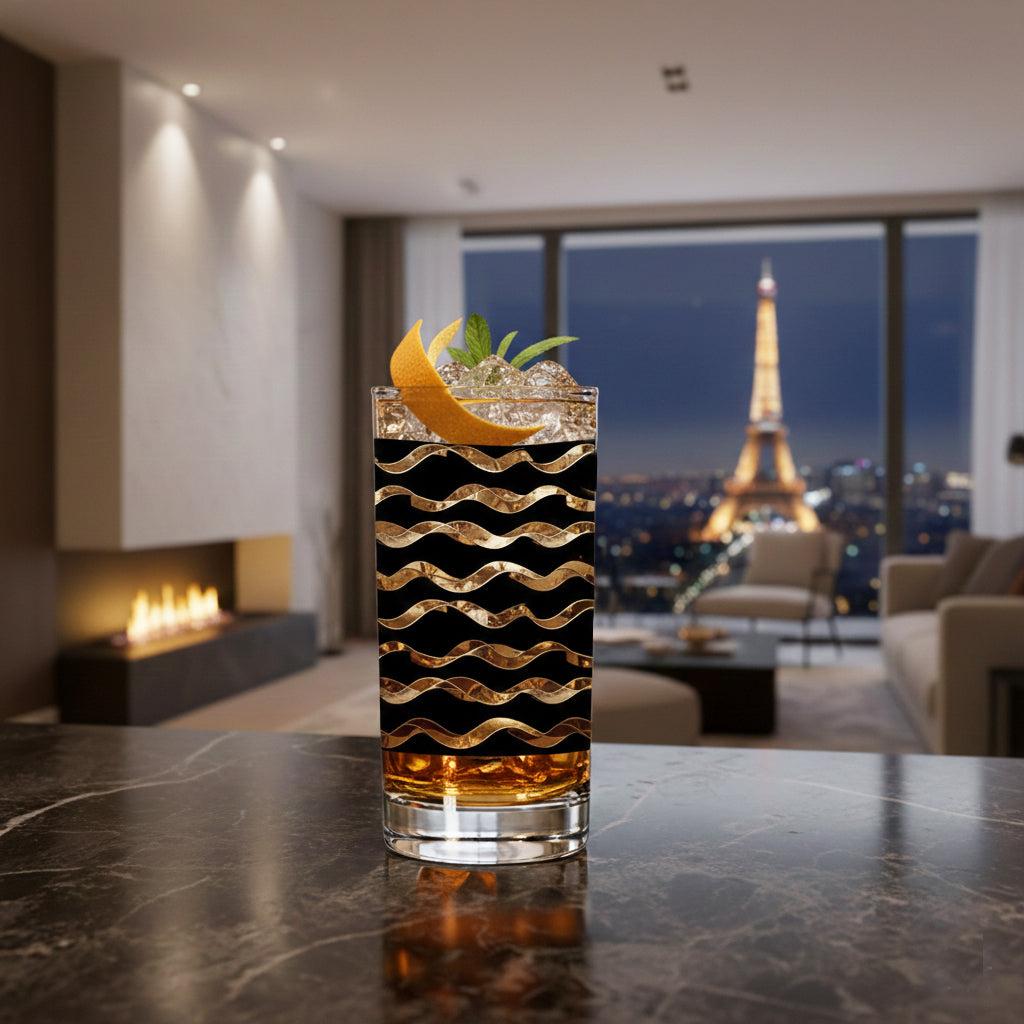 black and gold full-wrap design highball glass filled with cocktail and the Eiffel Tower in the background