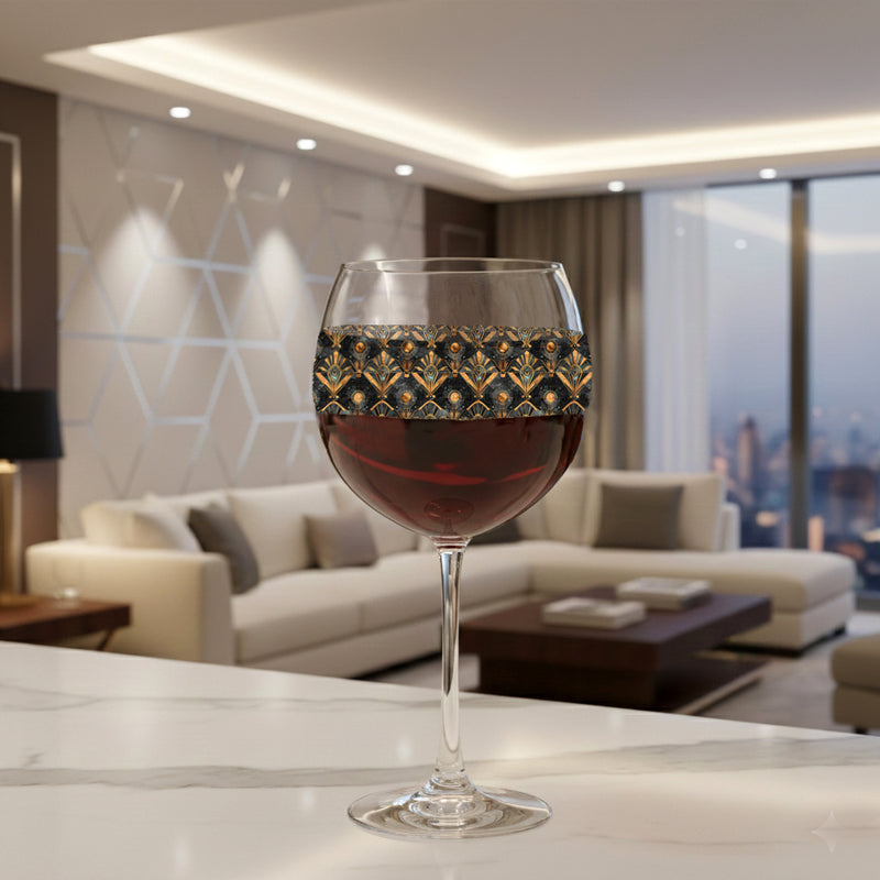 Astral Glow balloon wine glass with  a black and bronze design, filled with red wine on a marble surface with a modern living room in the background