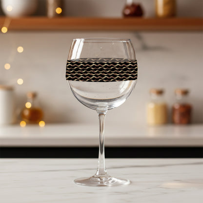 Liquid Gold balloon wine glass with black and gold wavy design on a blurred kitchen background