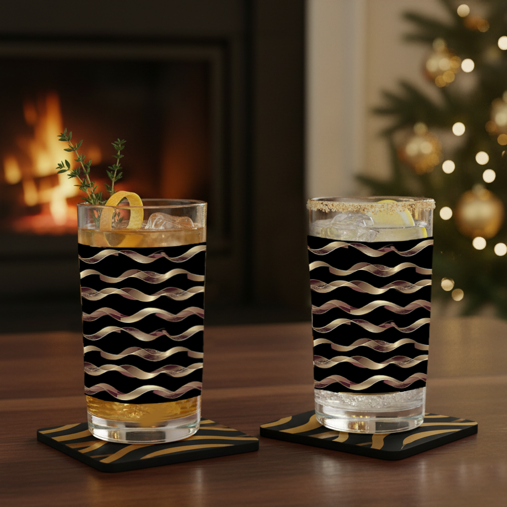Two Liquid Gold highball glasses in a black and gold wavy design with drinks on a table in front of a fireplace and Christmas tree.