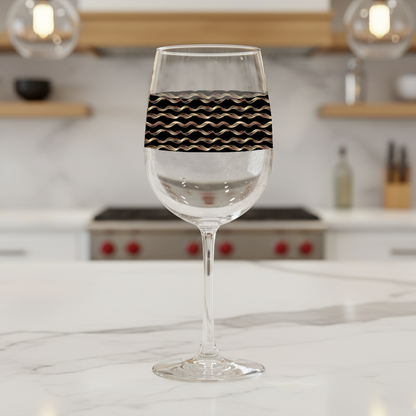 Liquid Gold tall wine glass with black and gold wavy design on a marble kitchen counter and blurred background.