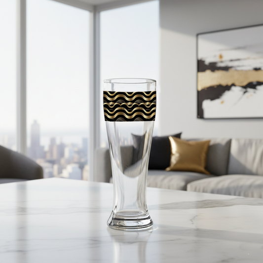 Liquid Gold pilsner beer glass with black and gold wave design on a marble surface in a modern living room.