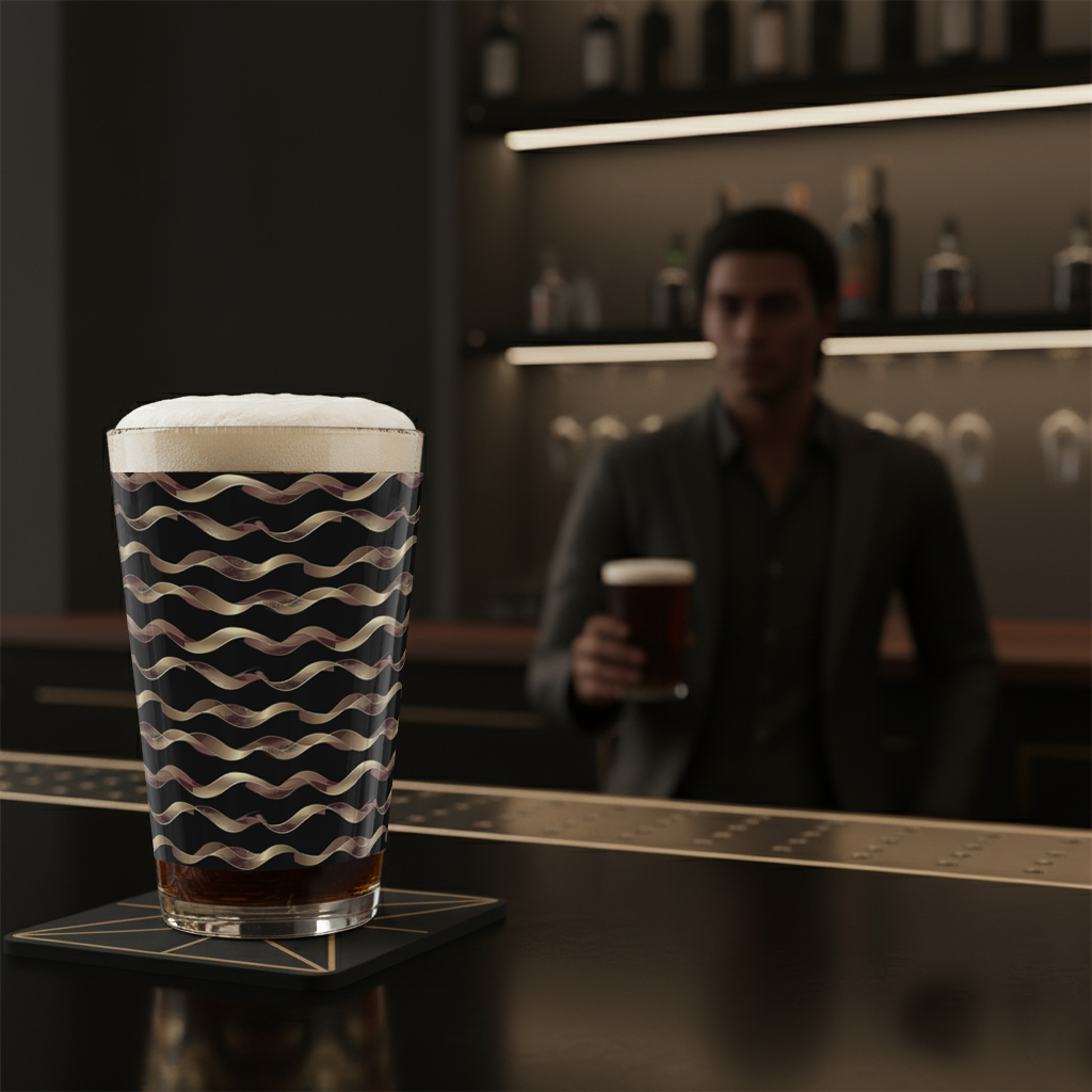 Liquid Gold pint glass of beer with black and gold wavy design on a bar counter,and blurred bar scene in the background
