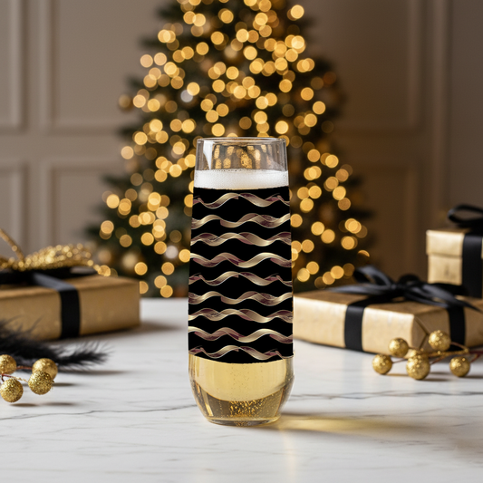 Liquid Gold stemless champagne glass with black and gold wavy design on a festive background with Christmas tree and presents.