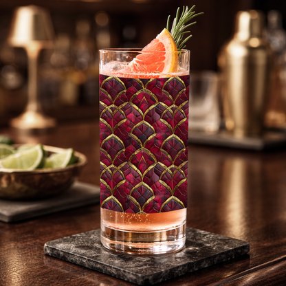 Crimson Jewels highball glass with a ruby and gold design, filled with a cocktail and garnished on a dark surface.