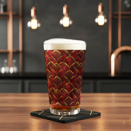 Crimson Jewels shaker pint glass with red and gold art deco design and filled with beer and foam head, sitting on a bar with coaster