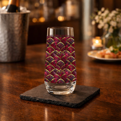 Crimson Jewels stemless champagne glass with a ruby and gold design on a table with a champagne bucket in the  background