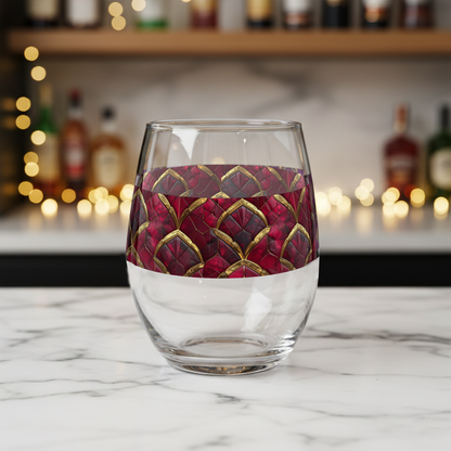 Crimson Jewels stemless wine glass with ruby and gold design on a marble surface with blurred bar background