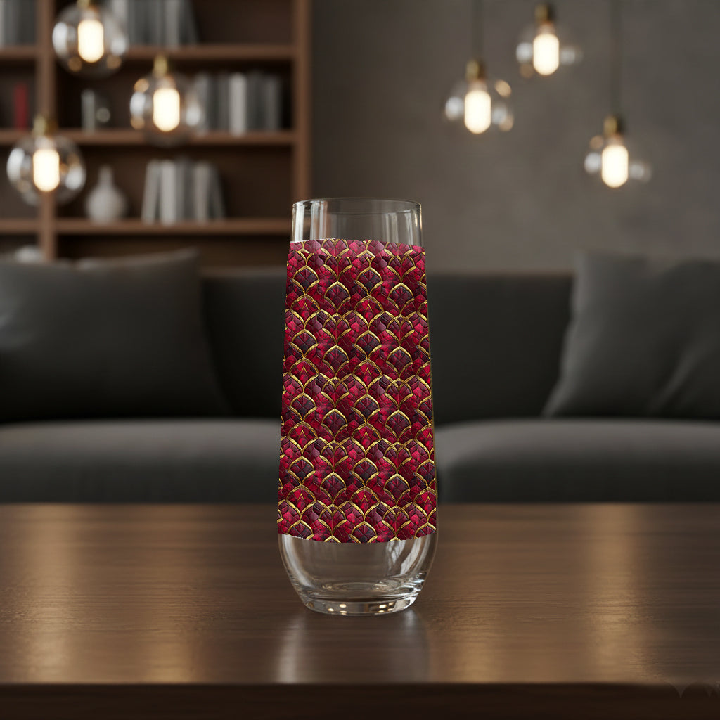 Crimson Jewels stemless champagne glass with a ruby and gold design on a table with a champagne bucket in the  background
