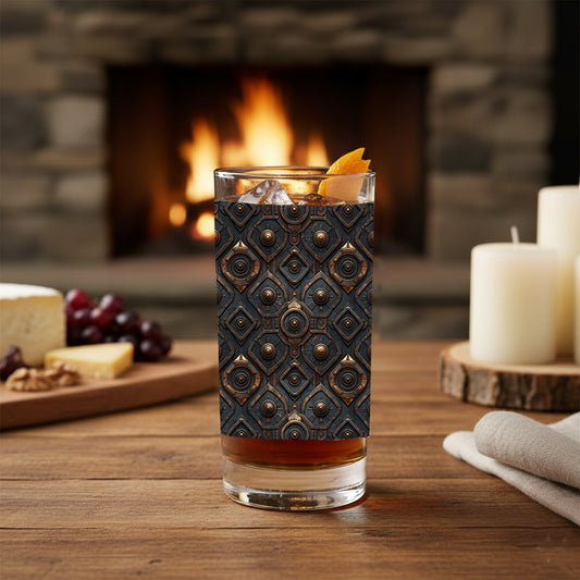 Foundtry Coppers highball glass with a dark ash discs design and filled with a cocktail sitting on a wooden table in front of a fireplace.