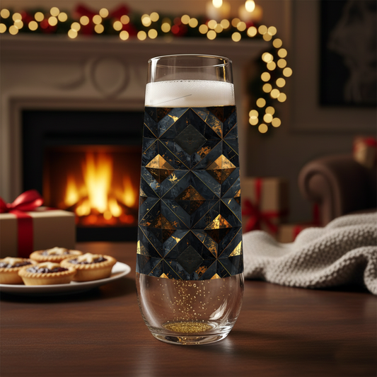 Gilded Decay stemless champagne glass with charcoal and gold geometric pattern on a table in front of a fireplace with Christmas decorations.