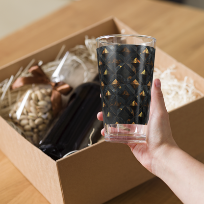 Hand holding the Gilded Decay pint beer glass with a charcoal and gold pattern over an open box.