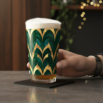 Emerald Royale pint glass with beer handheld, and a a green and gold pattern on a table with blurred background