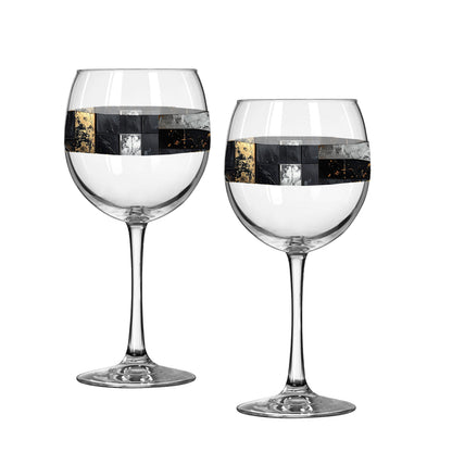 Two Fresco Fragments balloon wine glasses with black, silver, and gold design on a white background