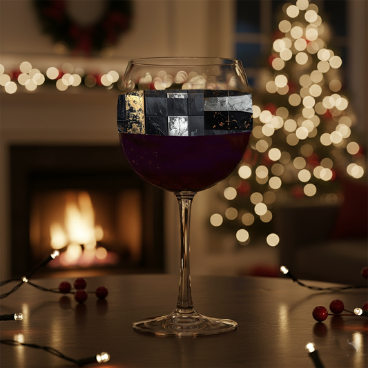 Freseco Fragments balloon wine glass with a band of aged patina fragments design against a festive background with lights and a fireplace.