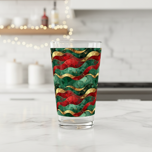 Royal Flux pint beer glass with red, green, and gold wavy design on a white kitchen counter with blurred background.