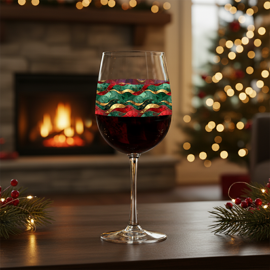 Royal Flux tall wine glass with red, green and gold wave design on a table in a cozy room with a fireplace and Christmas tree.