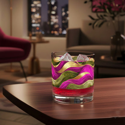 Colorful cocktail in an Aurelian Dusk rock glass with magenta, gold, olive design ad filled with ice on a table in a stylish living room with cityscape view.