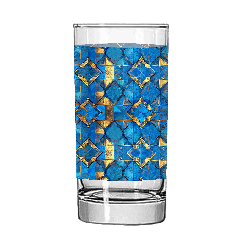 Clear highball glass with turqoise and gold geometric design on a white background