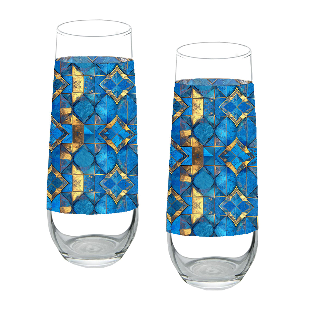 Two stemless champagne glasses with turqoise and gold geometric design on a white background