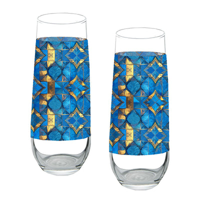 Two stemless champagne glasses with turqoise and gold geometric design on a white background