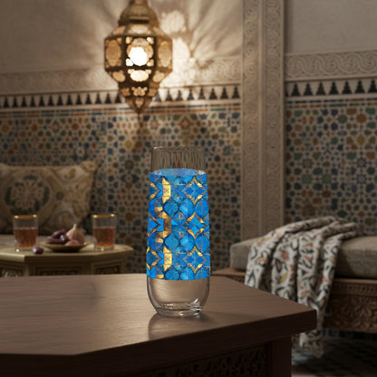 Moroccan Treasure stemless champagne glass with geometric blue and gold design sitting on a Mediterranean table with mosaic wall behind it and hanging lantern.