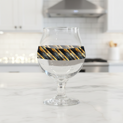 Obsidian Stripes Belgian beer glass with black and gold diagonal design on a kitchen counter