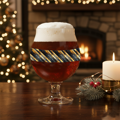 Obsidian Stripes Belgian beer glass with black and gold diagonal design in a festive setting with lights and candles.