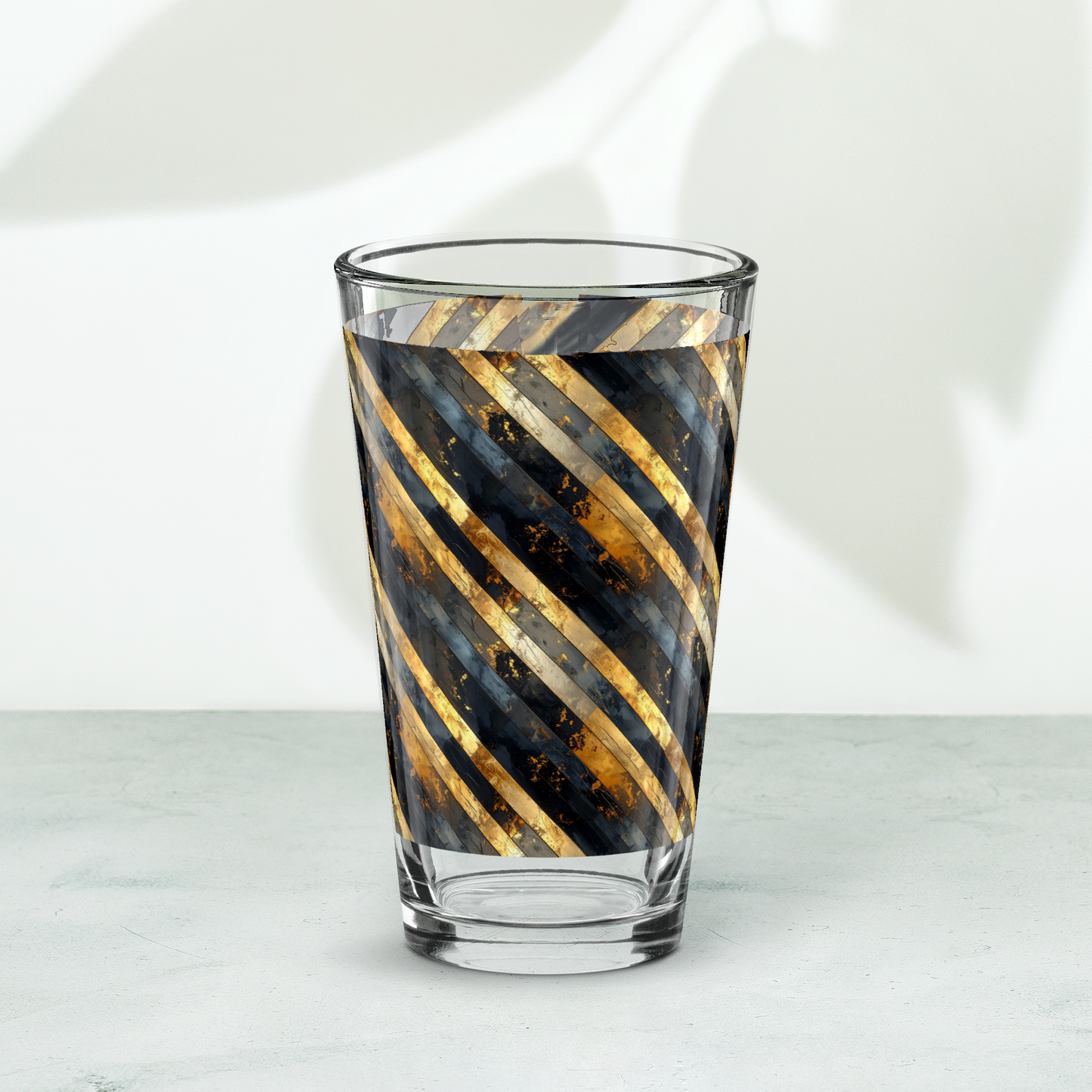 Obsidian Stripes pint ber glass with black and gold striped pattern on a white background