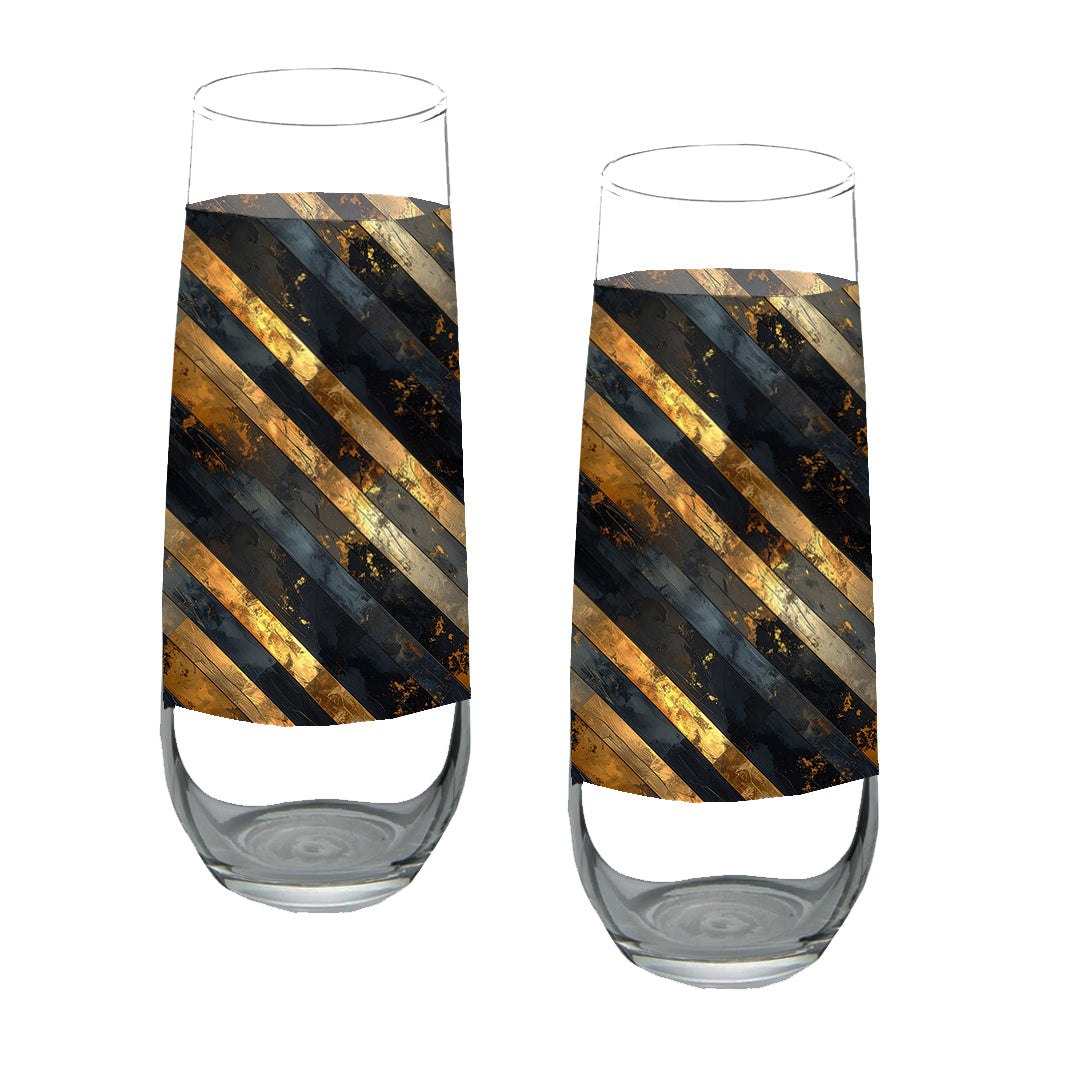 Two stemloess champagne glasses with black and gold striped design on a white background