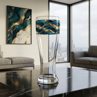 Opulent Teal pilsner glass with a teal and gold wave design on a bar counter with a cityscape view, people sitting with drinks, and colorful abstract painting in the background.