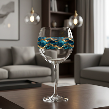 Opulent Teal balloon wine glass with  teal and gold design on a coffee table ithat is in  a modern living room settting with abstract art on the wall 