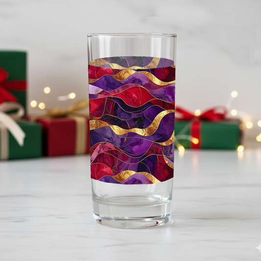 Fluid Marble highball glass with purple and gold design on a white surface with holiday gift boxes in the background.