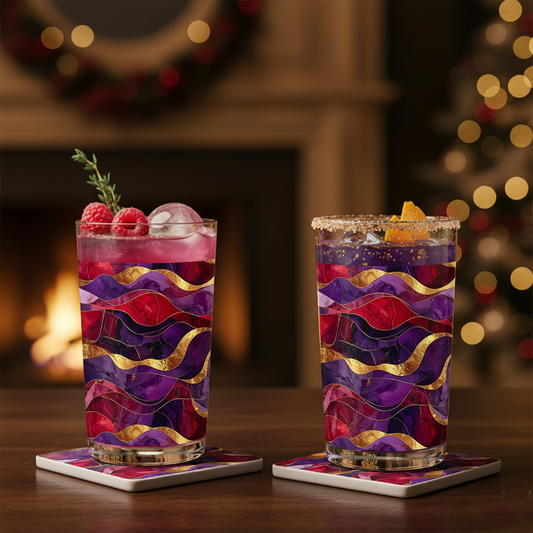 Two Fluid Marble highball glasses with purple and gold design, each filled with a cocktail on ice and garnish, on a wooden table with a blurred holiday background.
