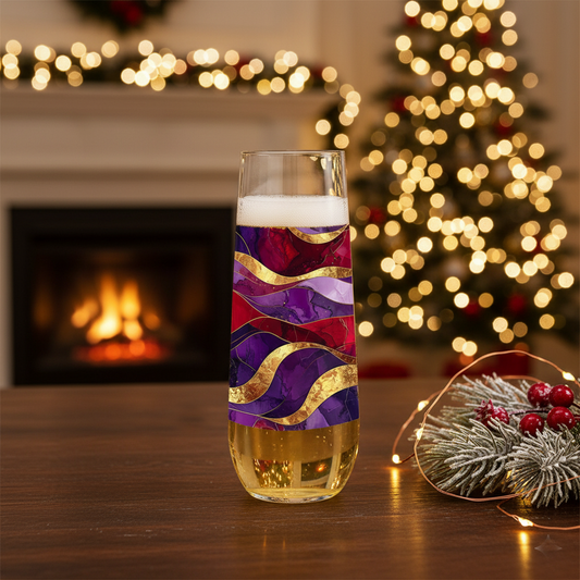 Fluid Marble stemless flute glass filled with champagne and in a purple and gold design on a table with a fireplace and Christmas tree in the background.