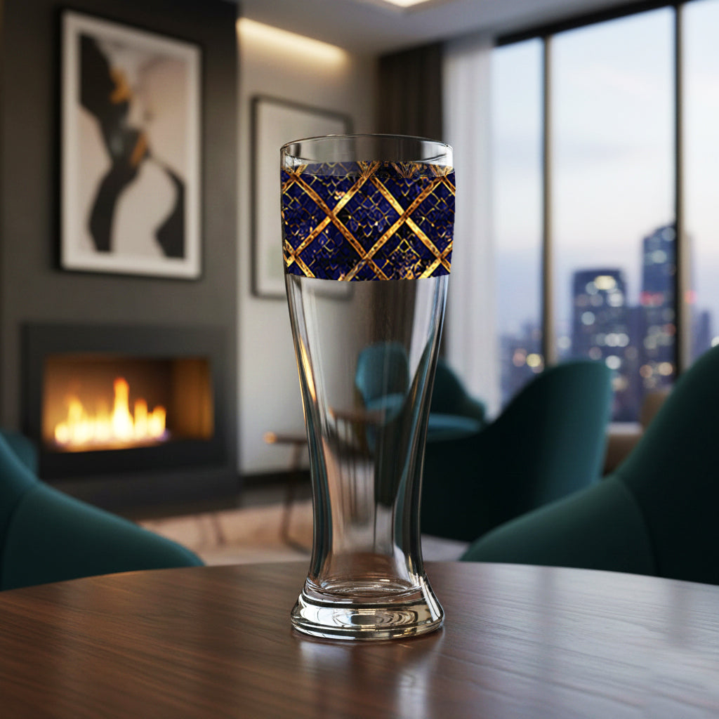 Regal Twilight pilsner beer glass with sapphire and gold wrap design on a table in a room with a fireplace and city view.