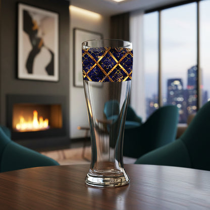 Regal Twilight pilsner beer glass with sapphire and gold wrap design on a table in a room with a fireplace and city view.