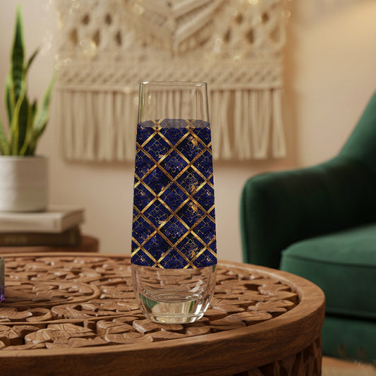 Regal Twilight stemless champagne glass with sapphire and gold wrap design on a wooden table in a cozy living room setting.
