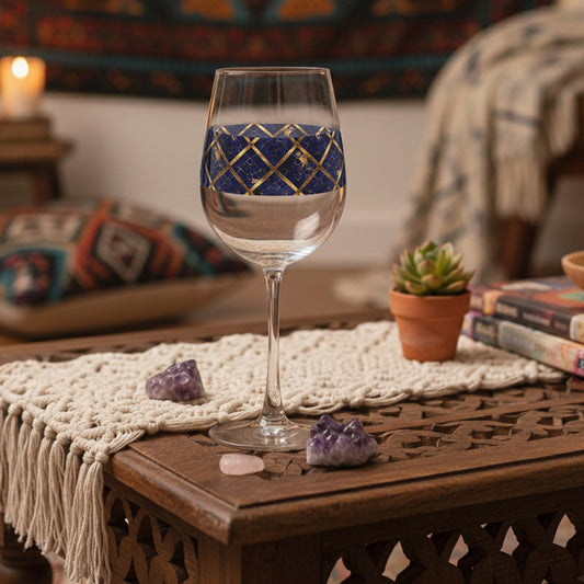 Regal Twilight tall wine glass with sapphire and gold pattern on a wooden table with crystals and a candle.