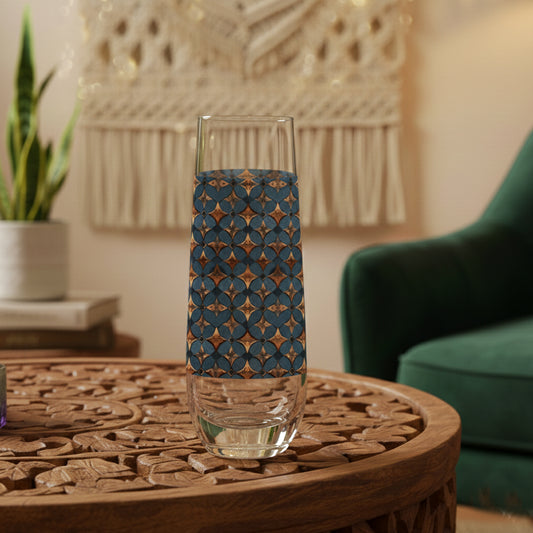 Burnished Slate stemless champagne glass with a slate blue and copper design on a wooden table in a cozy room.