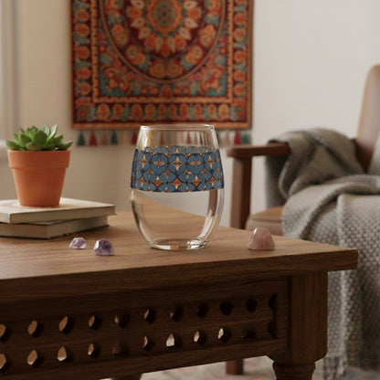 Burnished Slate stemless wine glass with slate blue and copper geometric pattern on a wooden table in a cozy living room.